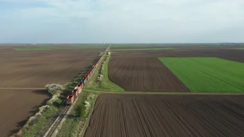 Above view of a freight train traveling with cargo carriages between plots 스톡 동영상 156732053