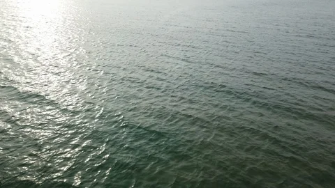 Above view of green water surface with waves and reflection of sun, 4k Stock Footage 129956546