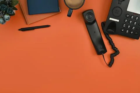 Above view of notepad, coffee up and telephone on orange background. Flat lay Stock Photos