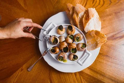 The above view of the person`s hand taking the snail shells full of the black Fotos Stock