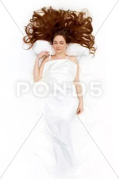 Above view of resting female under linen sheet with her long hair spread on pill Stock Photos