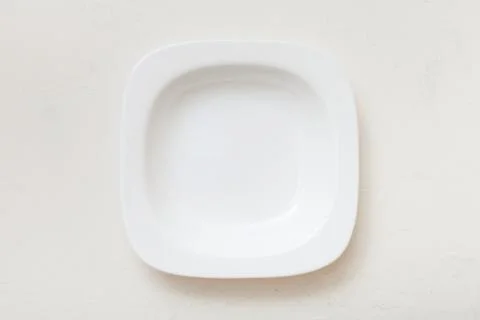 Above view of square white deep plate on plaster Stock Photos