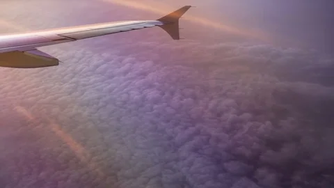 Above violet clouds with wing of airplane Stock Footage 73610979