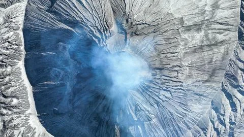 From above, the volcano ash covered slopes radiate from a steaming vent. Deep Stock Photos