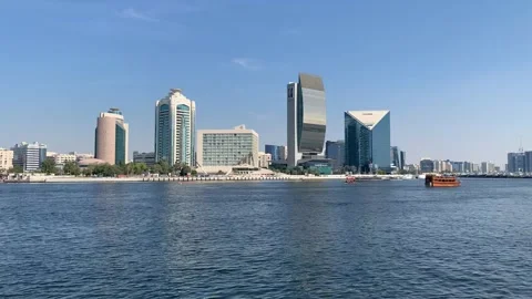 Abra boat sails through Dubai creek. Flag of the UAE is waving on top. Dubai Stock Footage 298917635