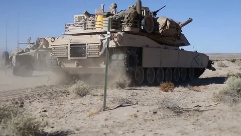 Abrams tank tracking past parked Humvee Stock Footage 84789687