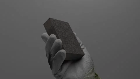 Abrasive sponge in hand on a gray background. Видео 265597768