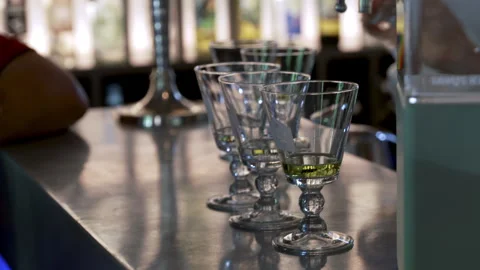 Absinthe glasses lined up on bar counter with green liquor in modern setting Vídeo Stock 333182686