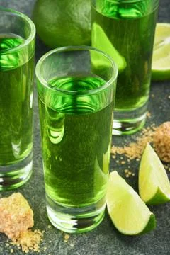 Absinthe. Two glasses of absinthe with cane sugar and lime on dark background Stock Photos