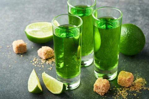 Absinthe. Two glasses of absinthe with cane sugar and lime on dark background Stock Photos