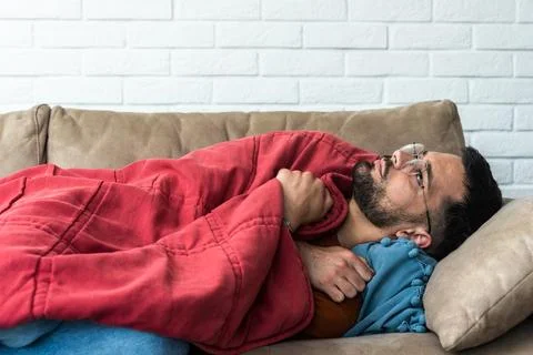 Absolute solitude. Side view of a depressed unhappy sad man lying on the so.. 스톡 사진