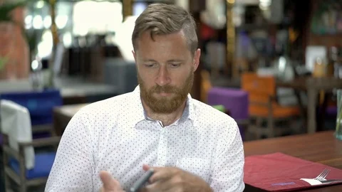 Absorbed man sitting in the restaurant and browsing internet on smartphone, stea 動画素材 81089243