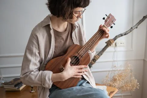 Absorbed woman practice string ukulele instrument with careful attention Stock Photos