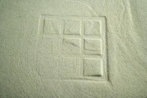 Abstract 3x3 grid pattern imprinted in fine, light-colored sand, featuring .. Stock Photos