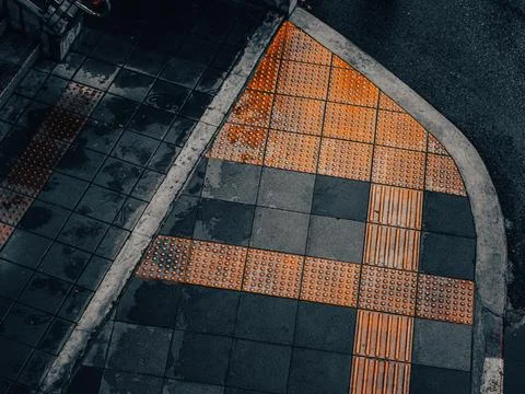Abstract Aerial Pattern of Orange Tactile Paving Arrow Design on Grey Sidewal Stock Photos