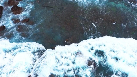 Abstract aerial view of ocean waves crashing on rocky shoreline. Stock Footage 112016875
