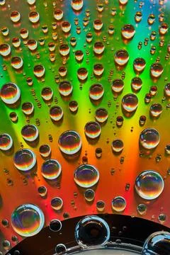 Abstract background asset metallic surface of rainbow colors with water droplets Stock Photos