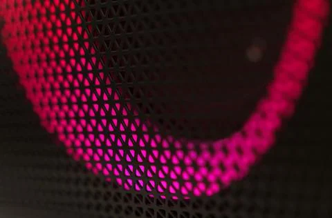Abstract background of a black patterned lattice behind which glow red LEDs 스톡 사진