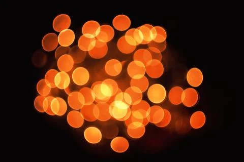 Abstract background with glowing orange bokeh light circles against a dark .. Stock Photos