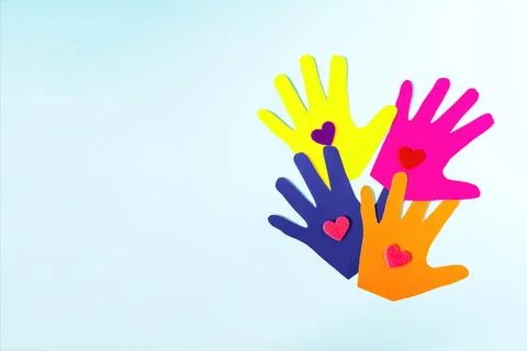 Abstract background made of colored paper and palms with bright hearts. Stock Photos