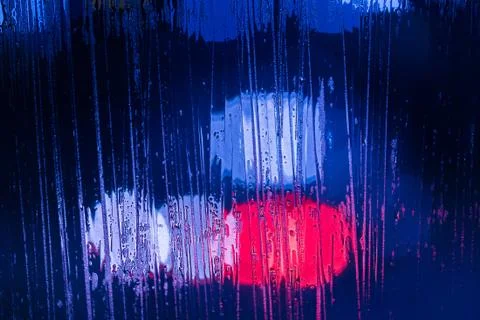 An abstract background of red and blue police lights bokeh trough wet glass at Stockfoto's