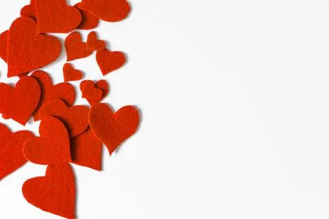 An abstract background of a scattering of bright red fabric hearts. Stock Photos