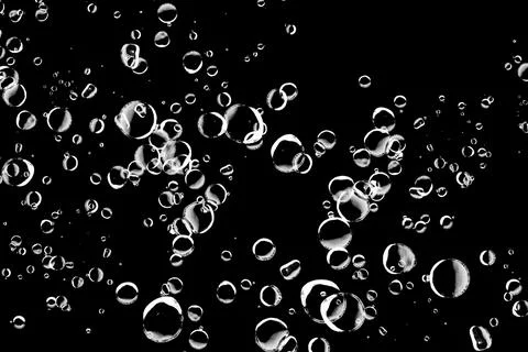 Abstract background of various sized bubbles floating on a black background.. Stock Photos