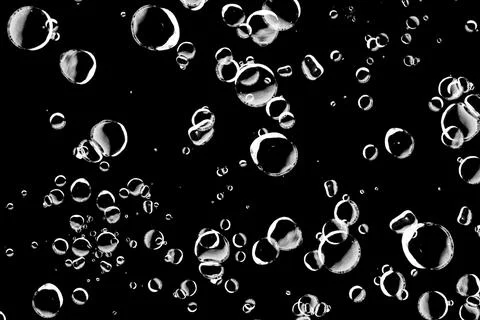 Abstract background of various sized bubbles floating on a black background.. Stock Photos