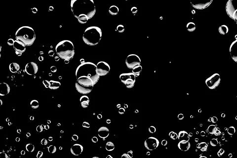 Abstract background of various sized bubbles floating on a black background. Stock Photos