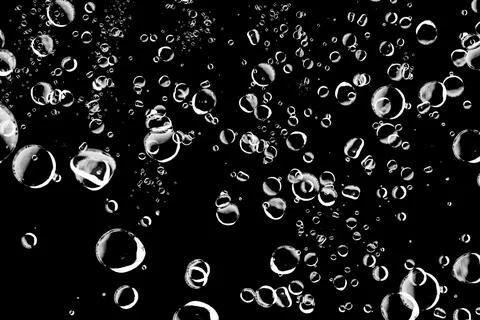 Abstract background of various sized bubbles floating on a black background.. Stock Photos