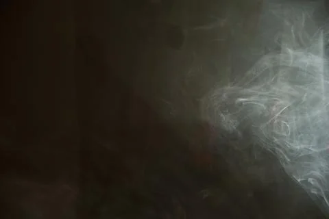 Abstract background of wispy white smoke drifting across a dark moody surface Stock Photos