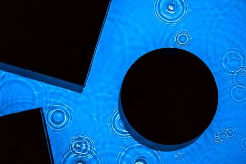 Abstract black geometric figures composition on transparent blue clear water Stock Photos