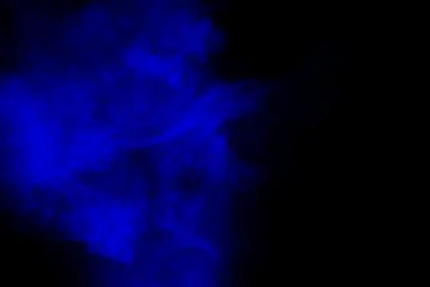 Abstract blue powder explosion cloud on dark background. Stock Photos
