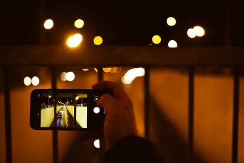 Abstract blur hand using mobile phone in the street.Night light,traffic jam b Stock Photos