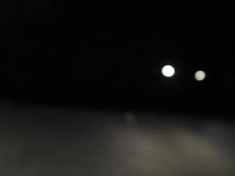Abstract blurred background with glowing white light circles in the dark night. 写真素材