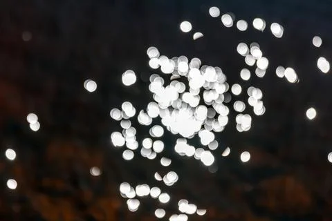 Abstract blurred bokeh lights creating a sparkling pattern over a dark surfac Stock Photos