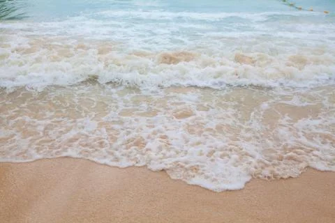 Abstract blurry background of soft wave of blue sea with sandy beach. Stock Photos