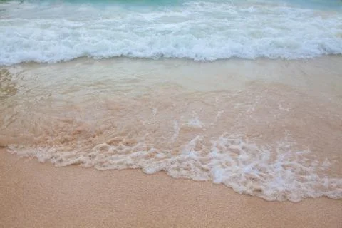 Abstract blurry background of soft wave of blue sea with sandy beach. Stock Photos