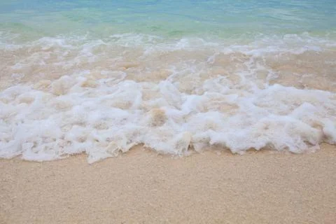 Abstract blurry background of soft wave of blue sea with sandy beach. Stock Photos