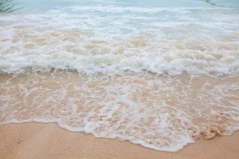 Abstract blurry background of soft wave of blue sea with sandy beach. Stock Photos