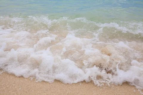 Abstract blurry background of soft wave of blue sea with sandy beach. Stock Photos