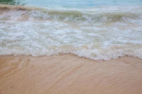 Abstract blurry background of soft wave of blue sea with sandy beach. Stock Photos