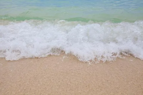 Abstract blurry background of soft wave of blue sea with sandy beach. Stock Photos