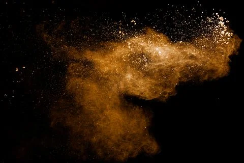 Abstract brown dust explosion on black background.Brown powder splashing. Stock Photos