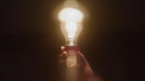 Abstract Close-up of Hand Holding Light Bulb that Lights up in Dark Studio Stock Footage 270304796