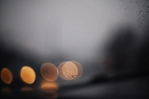 Abstract close-up of rainy windshield with blurry lights in dark moody weathe Stock Photos