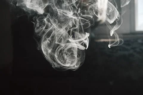 Abstract close-up shot of white smoke swirling against a dark background Stock Photos