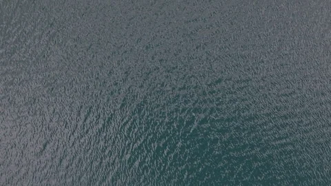 An abstract close-up view of subtle ripples on a dark blue-grey water surface Stock Footage 345618641
