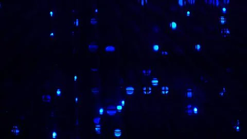 Abstract closeup of blue LED dots glowing through a dark grid, soft bokeh and Stock Photos