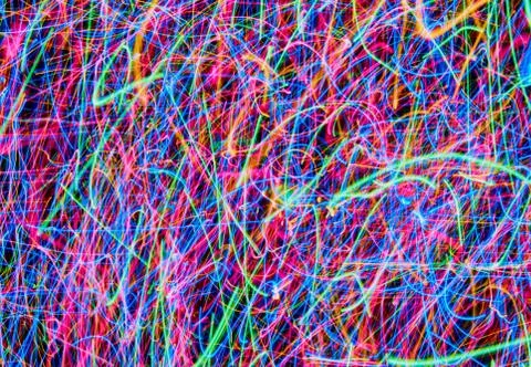 Abstract colored light lines on a black background. Blue, green, orange, pink. Stock Photos